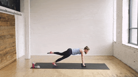 pregnant woman performing a high plank and leg lift into downward facing dog in a barre class workout at home