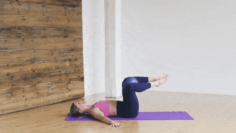 woman performing side to side leg lowers with pilates ball between knees to engage core