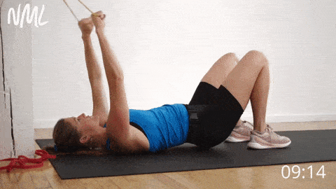 postpartum woman performing a glute bridge and band pull down as part of postpartum ab exercises workout