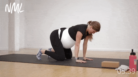 Pregnant woman performing a bear crawl hold as part of advanced prenatal yoga workout