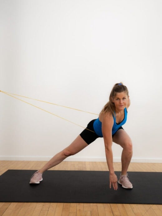 postpartum woman performing lateral lunge with a resistance band around her waist