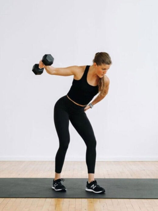 woman lifting dumbbell in right hand parallel to shoulder