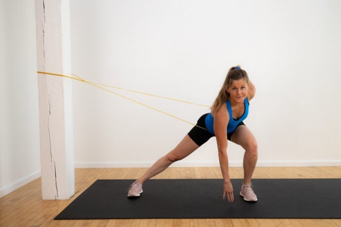 postpartum woman performing lateral lunge with a resistance band around her waist