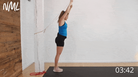 postpartum woman performing overhead lunges with a resistance band held overhead as one of the best postpartum ab exercises