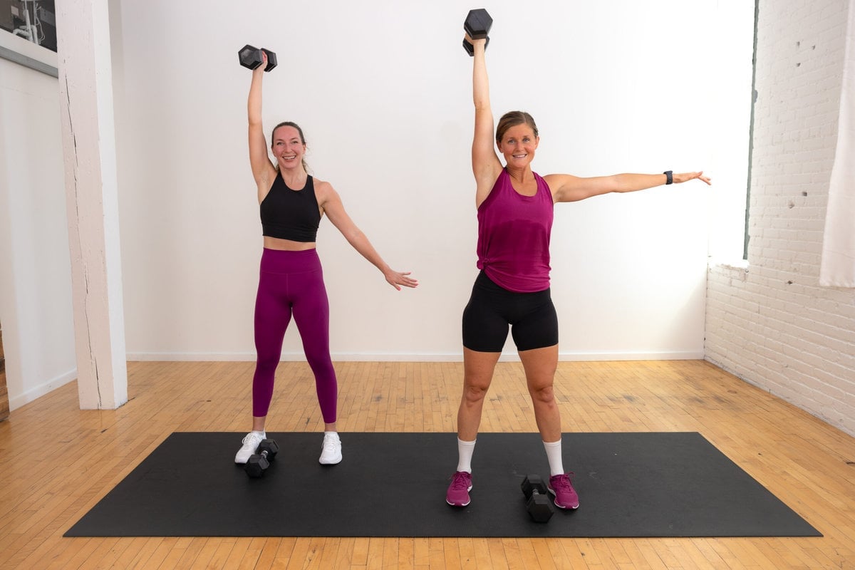 Two women performing a dumbbell snatch as part of a total body pyramid workout