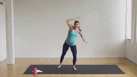pregnant woman performing an oblique crunch and side kick in a cardio barre workout