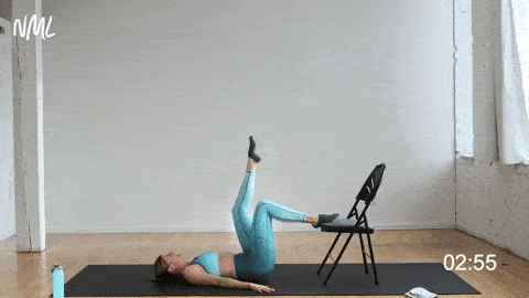 woman performing a single leg glute bridge with her foot elevated on a chair in a cardio barre workout