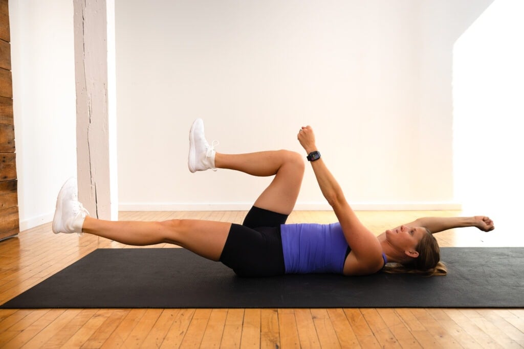 woman lying on her back performing a standard dead bug exercise