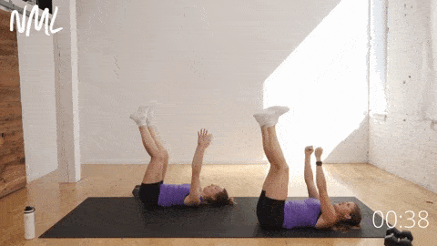 two women lying on their backs performing a straight leg dead bug exercise