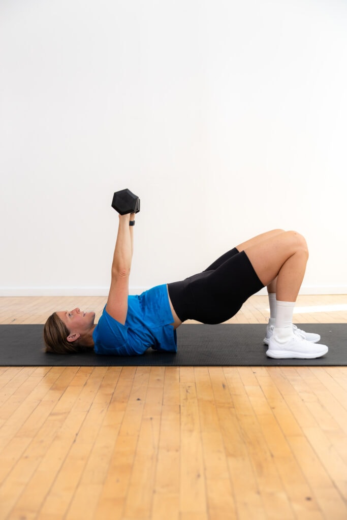 woman lying on her back performing a dumbbell chest press as example of strength training exercise for women