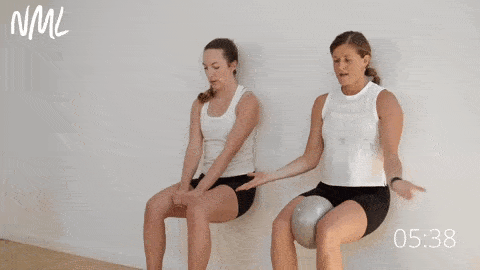 two women performing a wall sit as part of an inner thigh workout