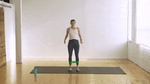 woman performing side to side squats with a resistance band
