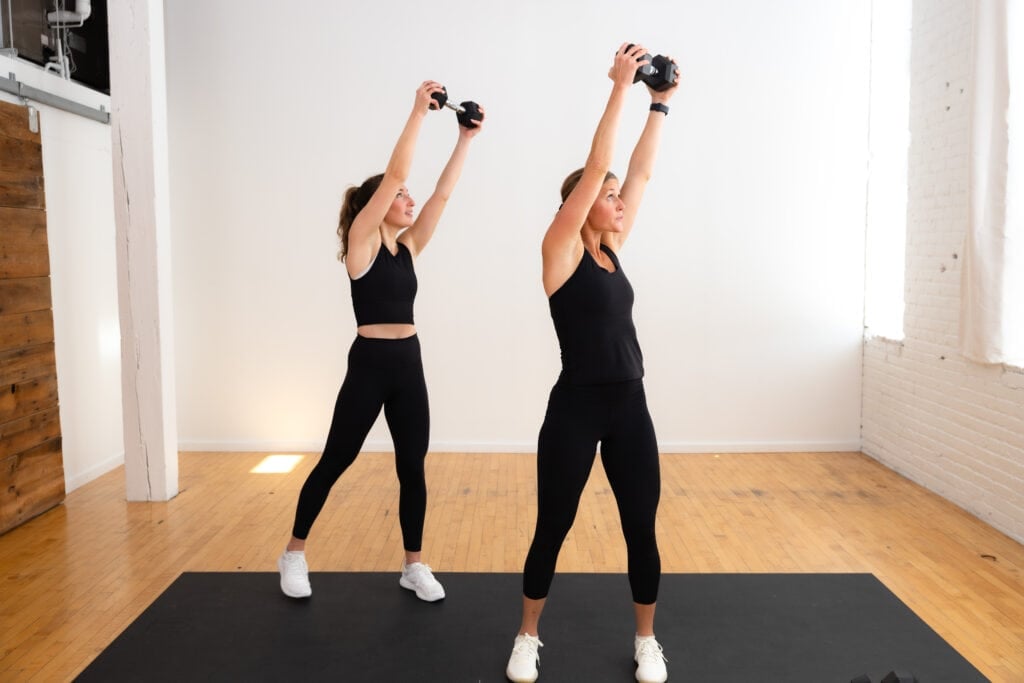 two women performing a diagonal lift as part of core workouts with weights