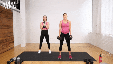 two women performing 2 dumbbell squats and a 2-second dumbbell squat hold in a legs, thighs and abs workout