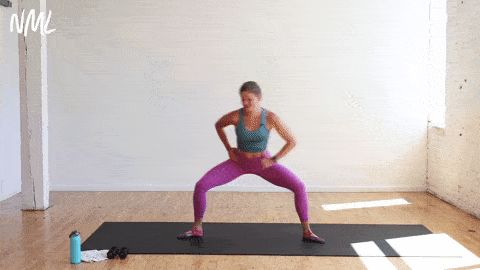 woman performing horse pose and a crossbody reach in a yoga sculpt workout