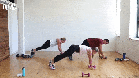 three people performing a high plank and open to T with dumbbell pulled overhead in a circuit training workout