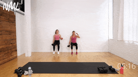 two women performing a wall sit and dumbbell pass in a legs, thighs and abs workout