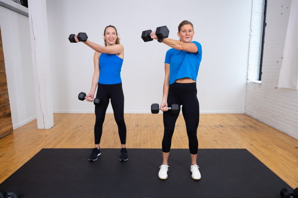 two women performing a standing chest fly as part of back and arm workout