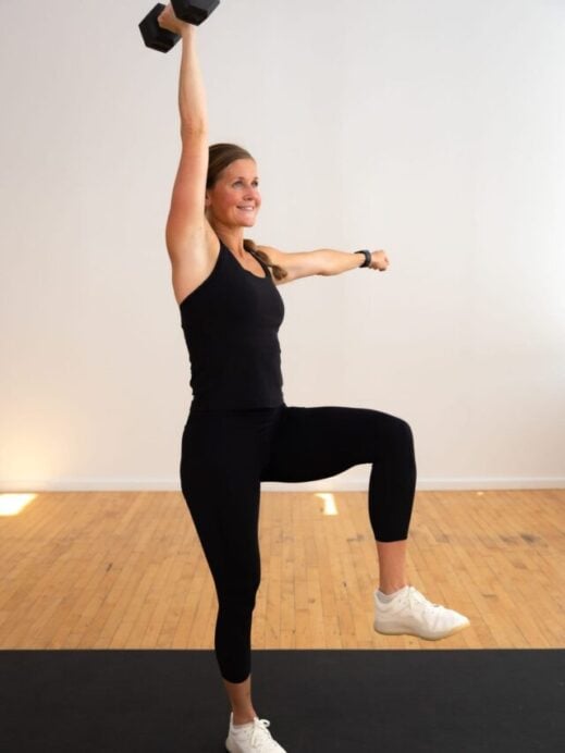 woman performing a overhead press in a core workout with weights