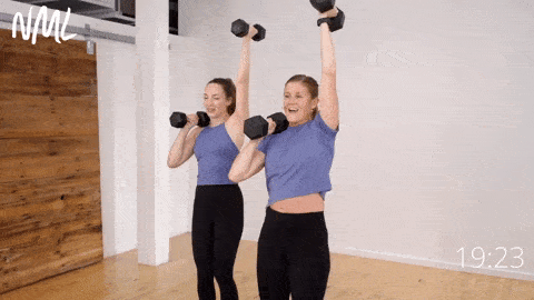 two women performing knee drives with a front rack and overhead hold as part of functional core training workout