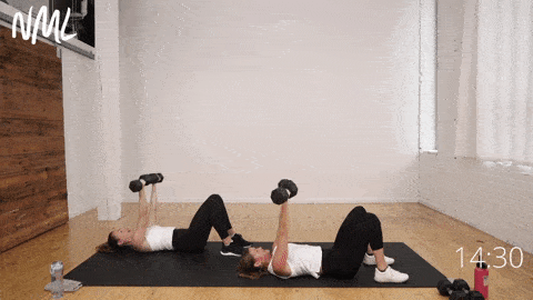 two women lying on their backs performing reverse grip chest presses as part of chest and leg workout at home