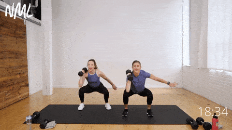 two women performing a squat and shouler press as part of core training workout