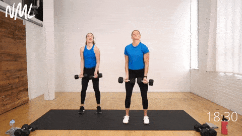 Two women demonstrating a standing chest fly as part of back and arm workout