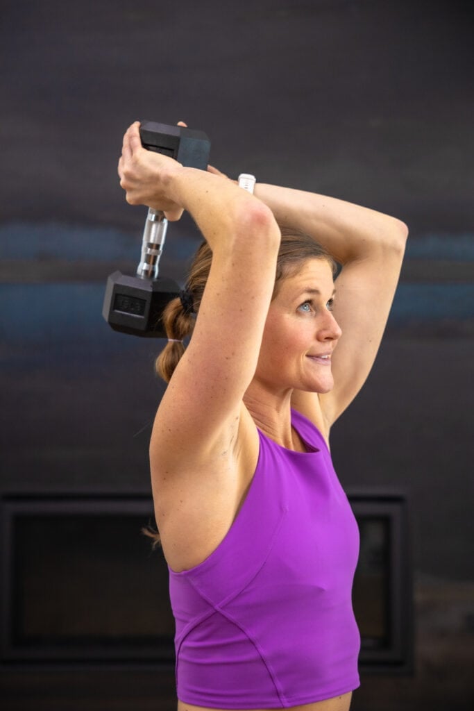 woman performing an overhead tricep extension with dumbbell