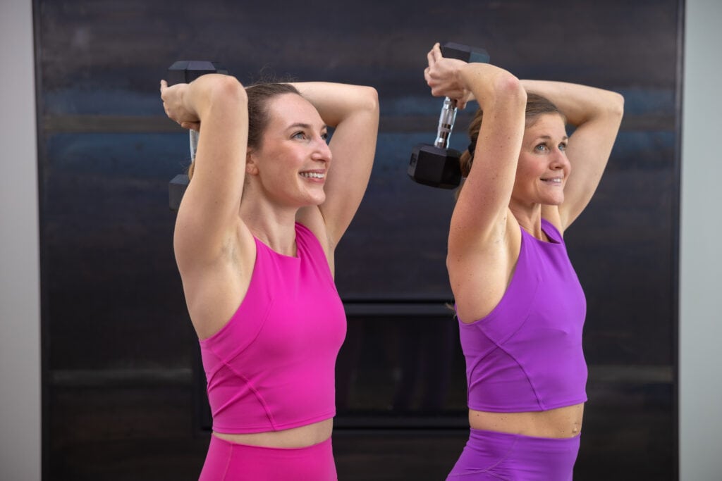 two women performing an overhead tricep extension as part of arm toning workout