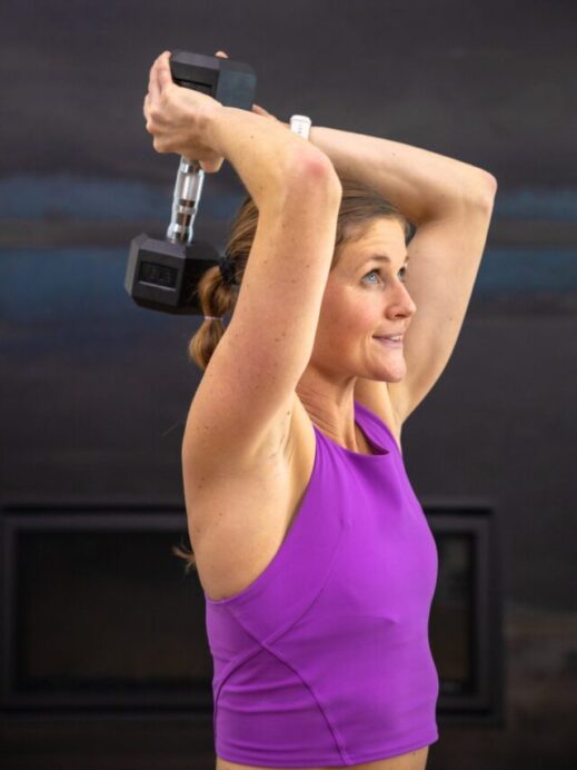 woman performing an overhead tricep extension with dumbbell