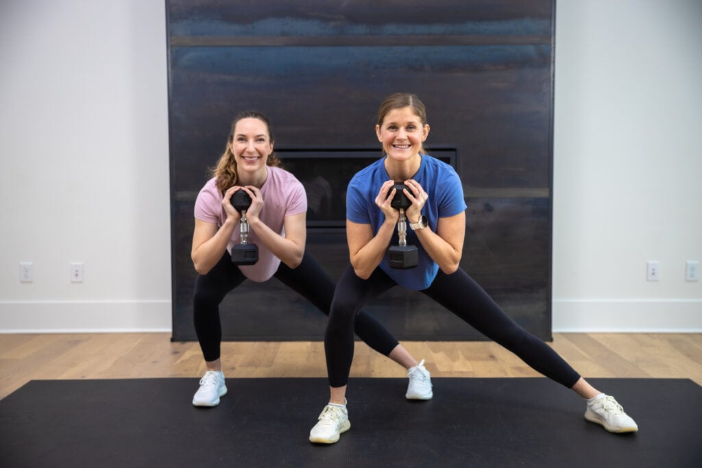 two women performing a lateral lunge as part of full body dumbbell workout