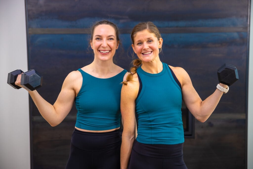 two women flexing biceps as part of bicep workout for women