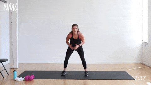 woman performing a wide to narrow squat jack and squat jump in a HIIT workout