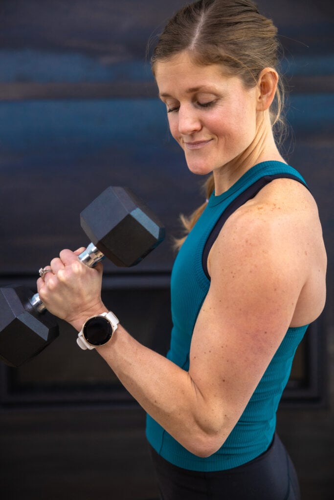 woman curling dumbbell to target the biceps as example of best bicep exercises