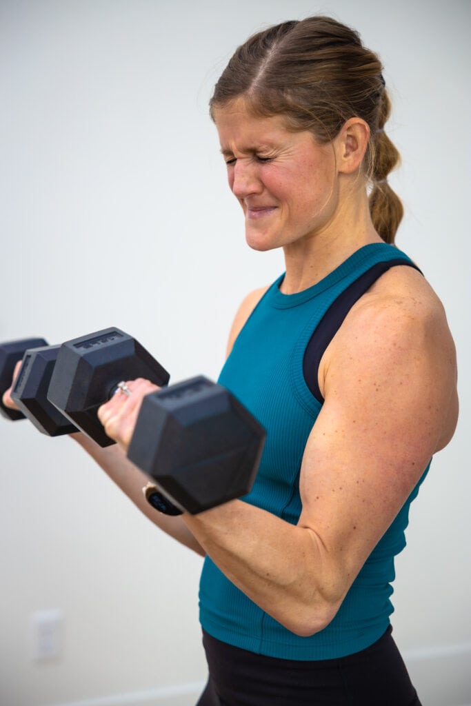 woman curling dumbbells as part of bicep workouts for women