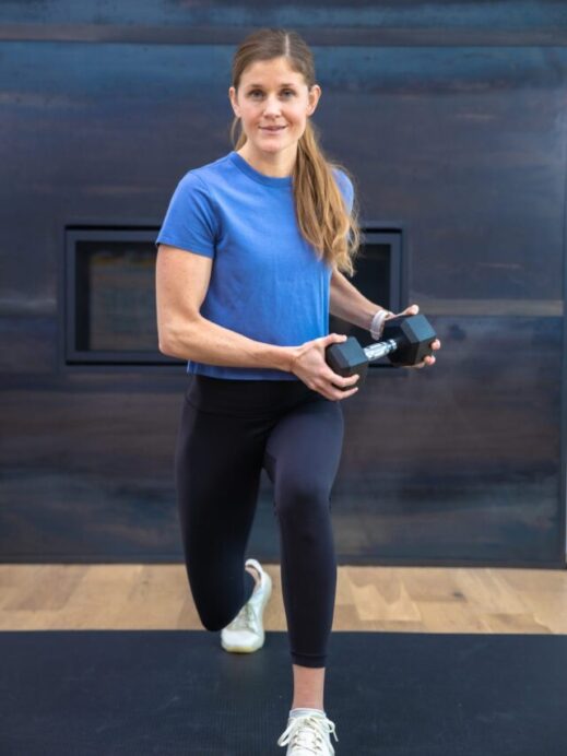 woman performing a lunge as part of full body dumbbell workout