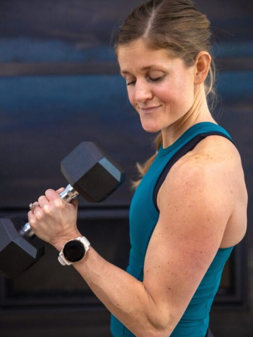 woman curling dumbbell to target the biceps as example of best bicep exercises