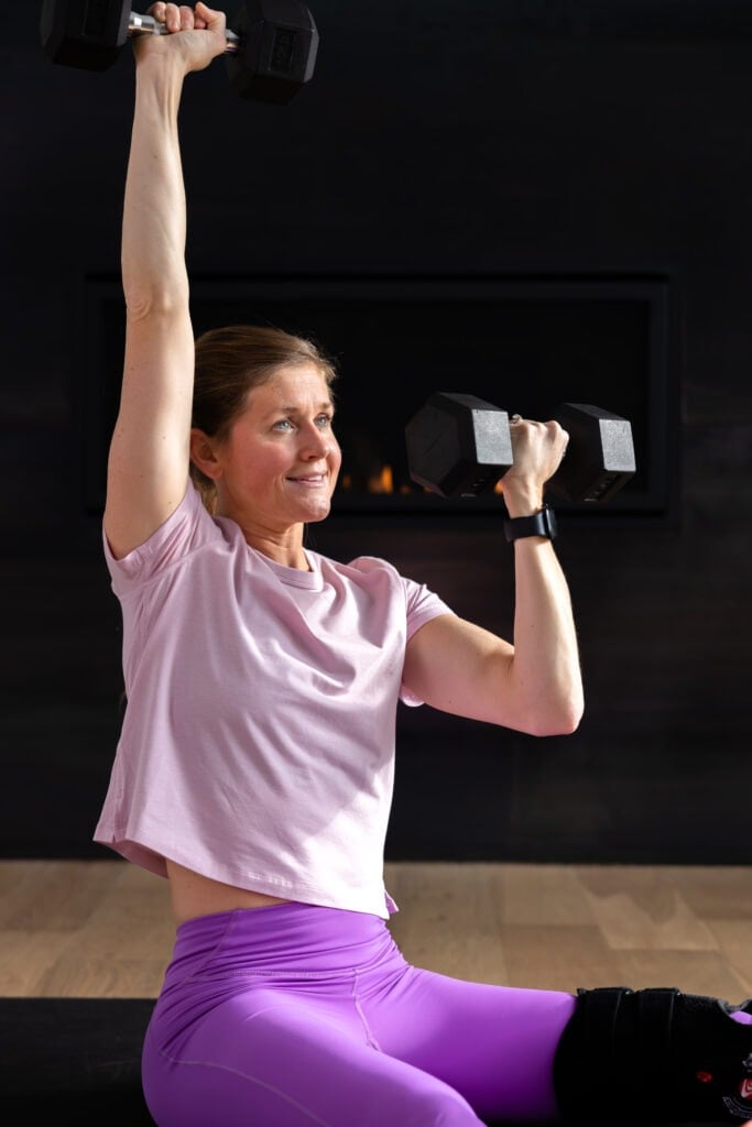 woman performing a seated shoulder press as example of floor exercise