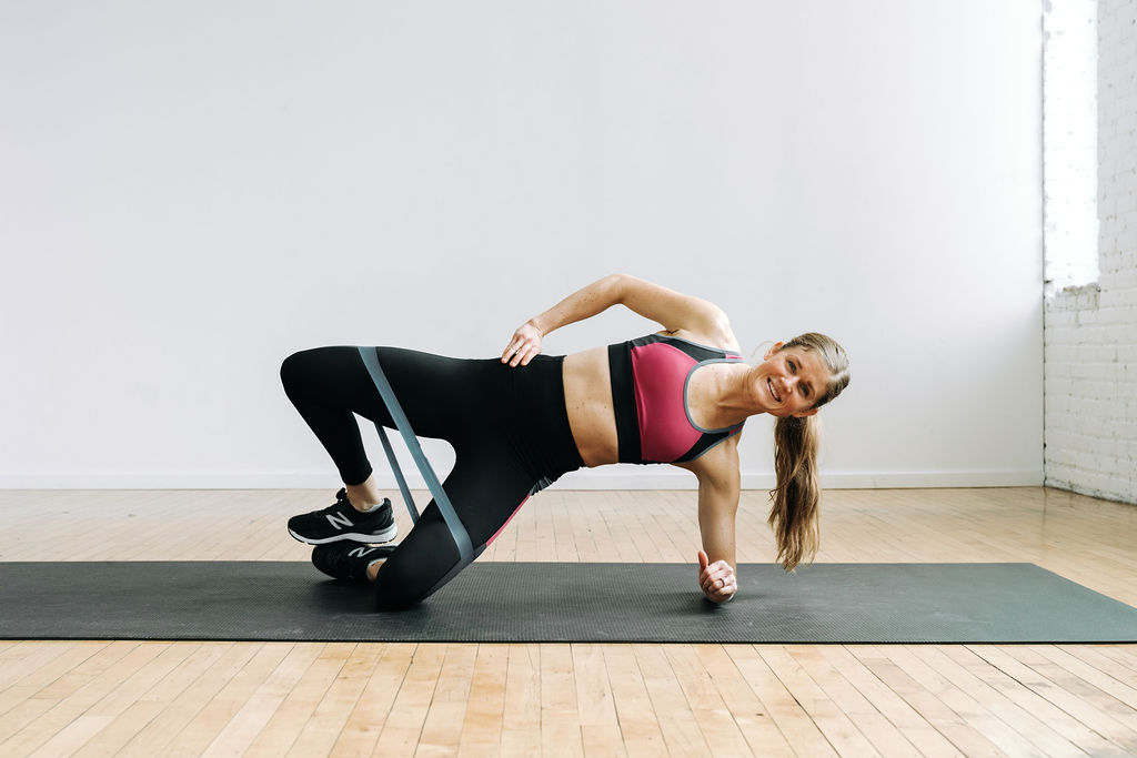 Women performing a clamshell during a lower body resistance band workout.