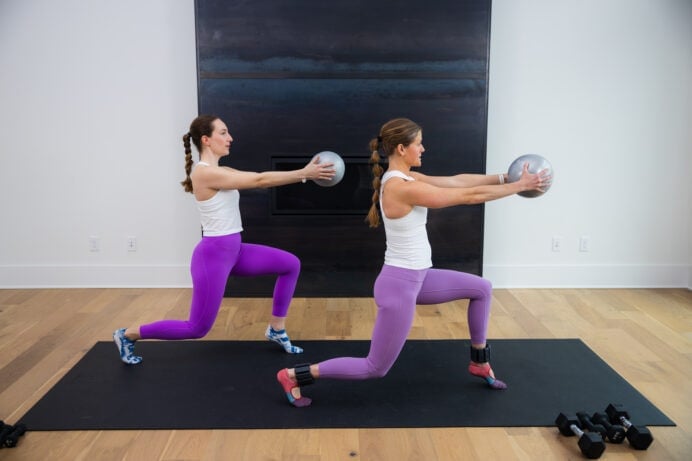 two women performing a step back lunge hold + ball press in a pilates class at home