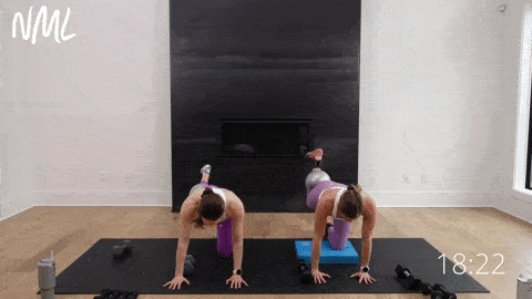 two women performing hamstring curl heel stamps with a pilates ball behind the knee in a pilates strength workout at home