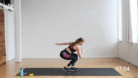 Women doing a staggered squat and doing a leg extension by kicking the left leg back in a resistance band leg workout. 