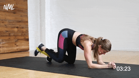 Women in table top position with resistance band around the soles of the feet, performing a one leg leg kick back with straight leg lift. 