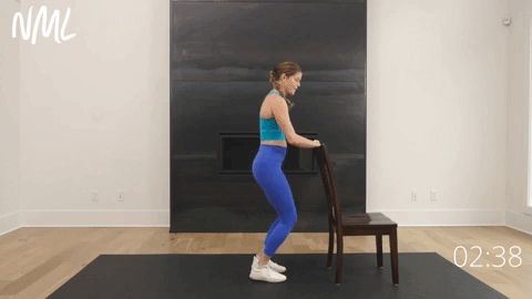 woman using chair for balance as she performs knees over toes calf raises