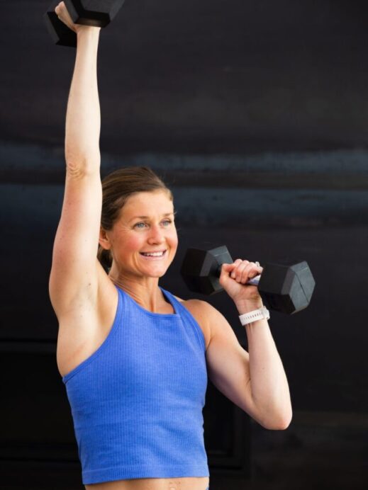 woman performing a single arm overhead press in an upper body hiit workout