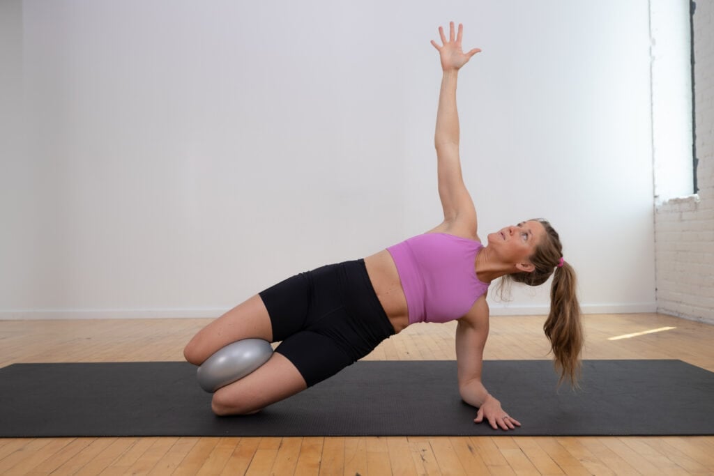 woman performing a supported side plank as example of exercise to heal diastasis recti.