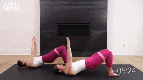 two women lying on their backs performing glute abductor opens with a resistance band