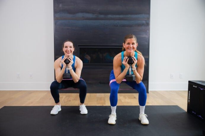 two women performing goblet squats with dumbbells as part of booty building workout for women