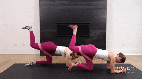 two women performing quaderuped donkey kick heel stamps as part of glute workout at home 