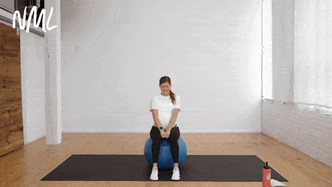 pregnant woman sitting on an exercise ball performing seated adductor contractions as example of pregnancy ball exercise